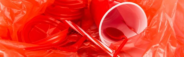 Plastik buruşuk dokuda kırmızı tek kullanımlık nesneler, panoramik çekim - Fotoğraf, Görsel