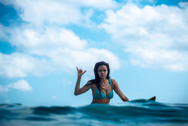 Portrait of surfer girl on white surf board in blue ocean pictured from the water in Bali - Zdjęcie, obraz