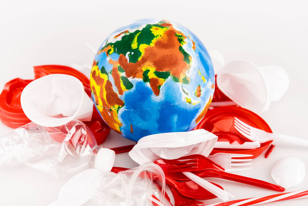 plastic trash scattered around globe on white background - Foto, Bild