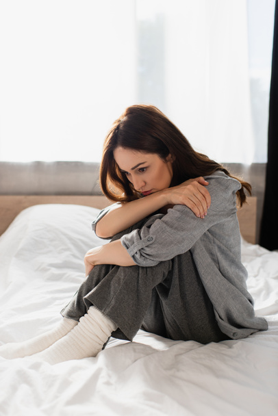 depressed brunette woman sitting on bed at home - Photo, Image