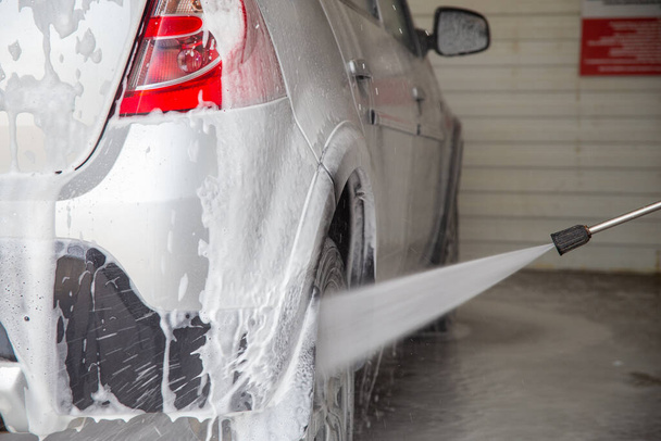 una vista de primer plano del proceso de lavado de automóviles mojados en interiores - Foto, Imagen
