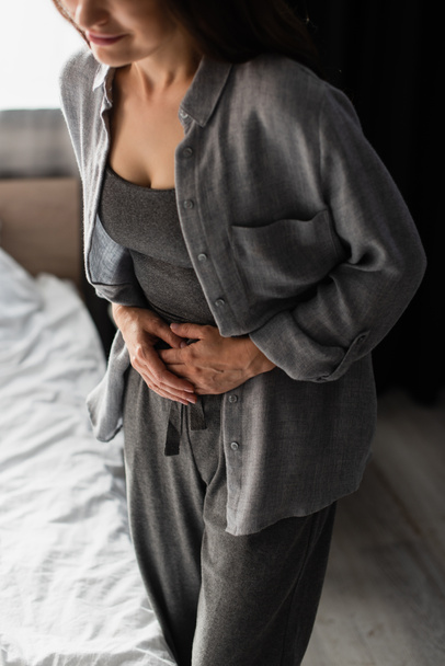 partial view of woman having stomach ache in bedroom  - Foto, Imagem