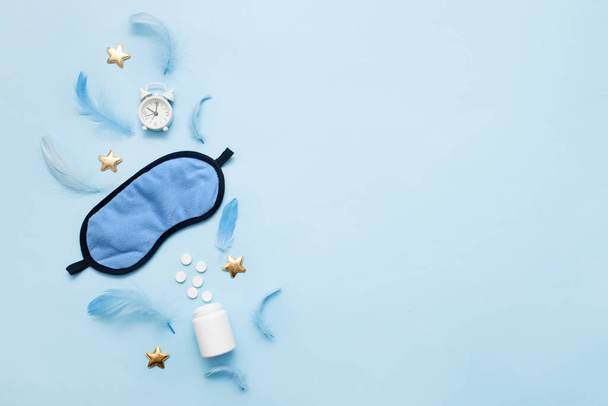 Pills, bottle, sleeping mask and white alarm clock with stars on blue pastel background. Concept Insomnia, sleep problems, time to take pills and treatment. Top view, flat lay, copy space - Photo, Image