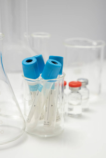 béchers, spécifications et tubes à échantillons de sang sur fond blanc - Photo, image