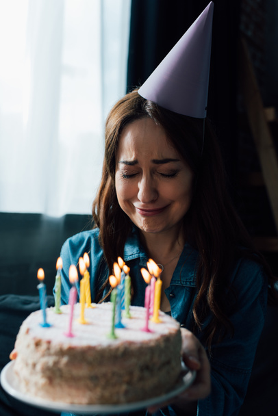 selective focus of upset woman crying while holding birthday cake with candles  - Фото, зображення