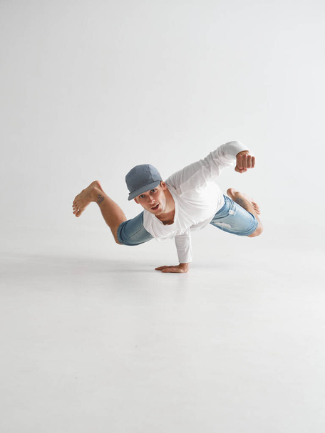 Cool guy breakdancer stands on one hand dancing lower break dance, isolated on white background - Фото, изображение