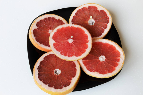 Frische Grapefruit auf einem schwarzen Teller. Gesunder Lebensstil. Veganes Essen. - Foto, Bild