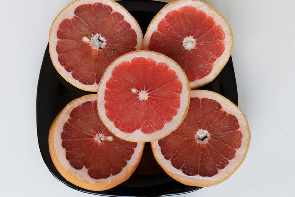 Fresh grapefruit on a black dish. Healthy food lifestyle concept. Vegan food. - Photo, Image