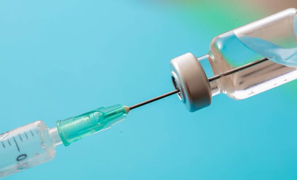 Impfung, Coronavirus-Impfung, Covid-19-Grippe-Prävention, Immunisierungskonzept. Vial-Dosis und medizinische Spritze, Medikamentenspritze, pastellblauer Hintergrund, Nahaufnahme. - Foto, Bild