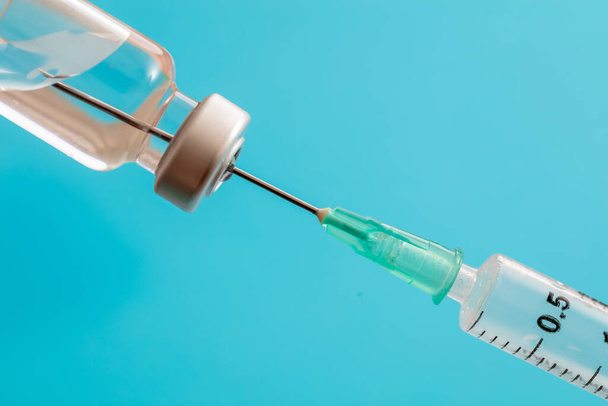 Вакцина, коронавирусная вакцинация, профилактика гриппа ковид-19, концепция иммунизации. Вязная доза и медицинский шприц, инъекции лекарств, пастельно-голубой фон, крупный план. - Фото, изображение