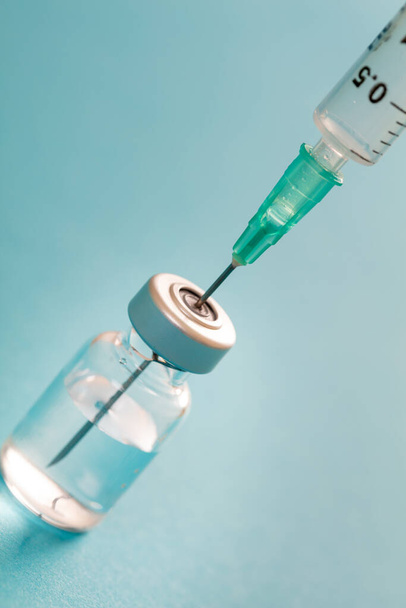 Vaccine, coronavirus vaccination, covid-19 flu prevention, immunization concept. Vial dose and medical syringe, drug medicine shot injection, blue background, closeup. - Photo, Image