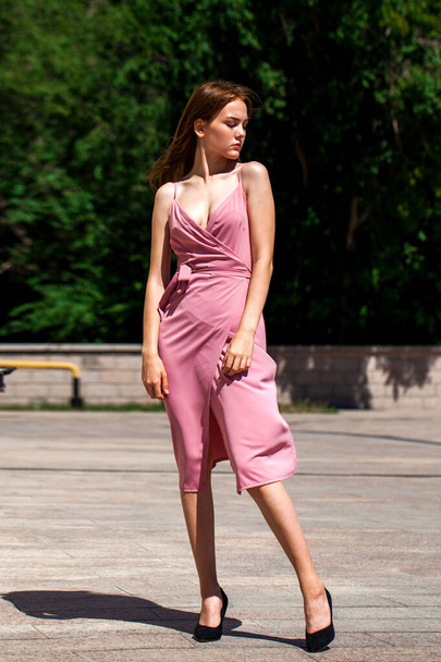 jong mooi brunette in een koraal jurk poseren op de straat bij zonnig weer - Foto, afbeelding