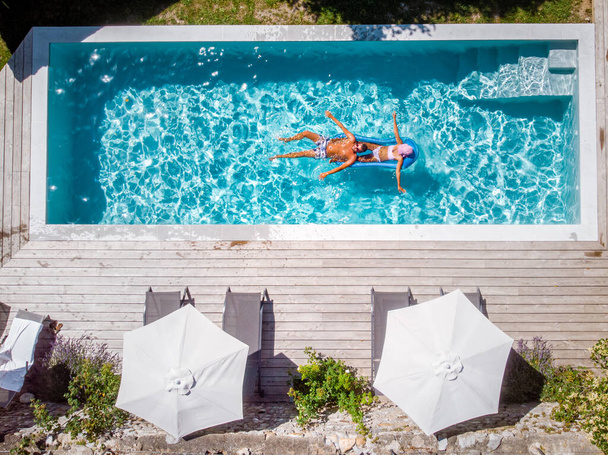 dwie osoby pływają w basenie w hotelu. Widok z góry, para mężczyzn i kobiet w basenie luksusowego domu wakacyjnego w Ardeche Francja - Zdjęcie, obraz