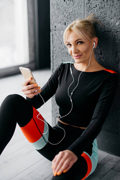 young slim woman listens music on player in gym - Zdjęcie, obraz
