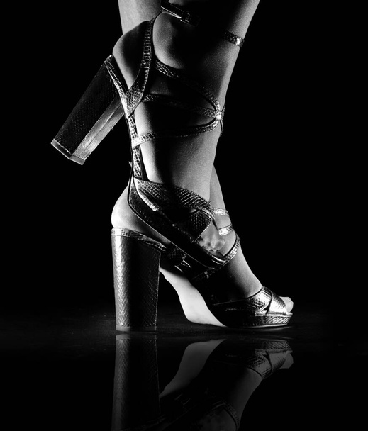 female feet in high heeled sandals on black backgroun - Foto, afbeelding