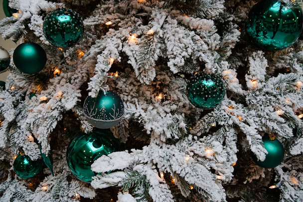 spar bedekt met sneeuw, versierd met groene bollen - Foto, afbeelding