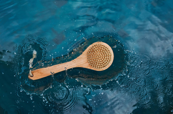 Eine Holzbürste aus natürlichen Kakteenborsten liegt auf dem blauen Wasser im Pool. Zero-Waste-Konzept - Foto, Bild