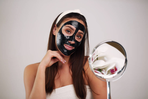Mulher bonita com uma máscara preta de limpeza em seu rosto. - Foto, Imagem