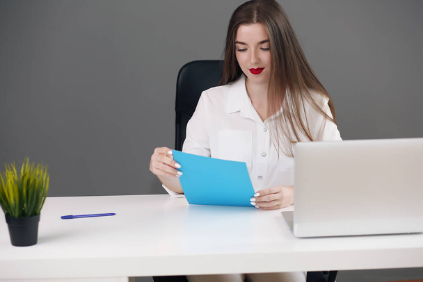 Business woman sitting at a desk with a laptop and looking away in the office - Photo, Image