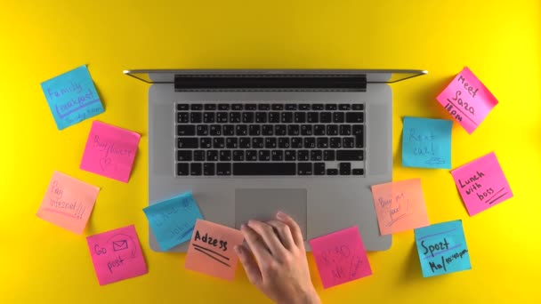 Utilice el ordenador portátil, colóquelo en el espacio de trabajo, tome notas en pegatinas, escritorio amarillo - Metraje, vídeo
