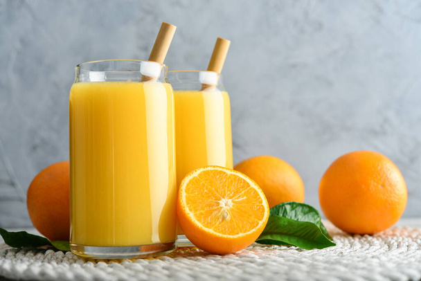 Two Glasses of Fresh Orange Juice with bamboo drinking straws on light wooden background - Foto, Imagem