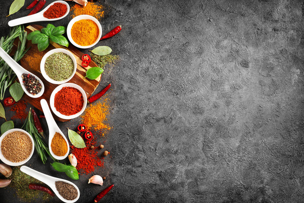 Top view of various spices in bowls and spoons on dark background. Copy space. - Foto, Bild