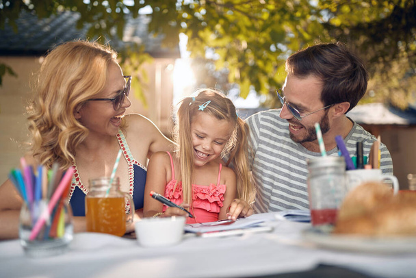 Happy family sitting at garden with their cute  daughter and spending time together. - 写真・画像