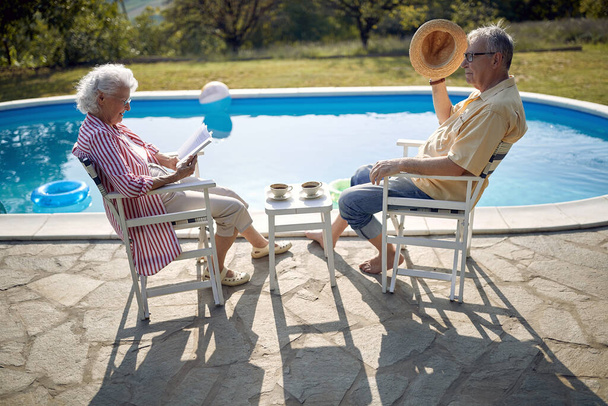 Senior man and woman enjoy on summer holiday near swimming pool together. - Фото, зображення