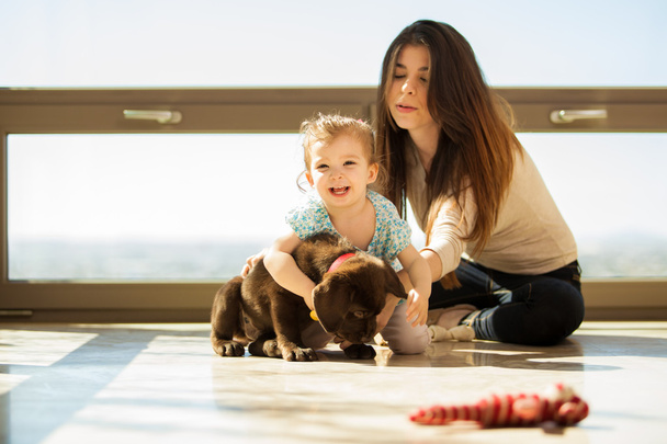 Mother and daughter playing with a dog - Photo, Image