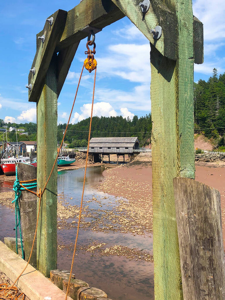 Colorful fishing boats and wooden covered bridge in Atlantic Canada on the Bay of Fundy, St. Martins, New Brunswick during low tide - Photo, Image