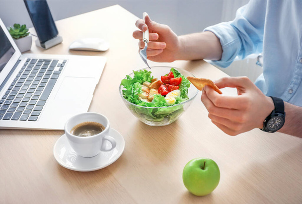 Almoço de negócios saudável no local de trabalho do escritório. Empresário que tem salada de legumes e frango em tigela na mesa de madeira perto do laptop
. - Foto, Imagem