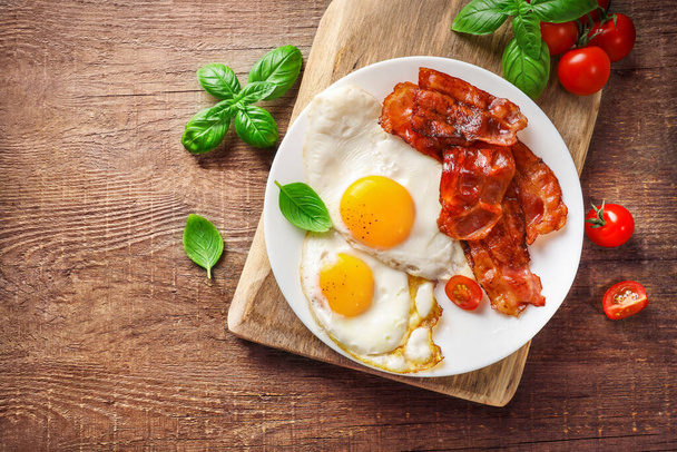 Full american breakfast with fried eggs and roasted bacon on wooden background. Top view. - Photo, Image