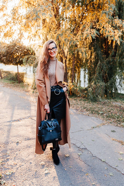 beautiful girl in a coat, black skirt and jacket autumn walks in a hat - Fotoğraf, Görsel