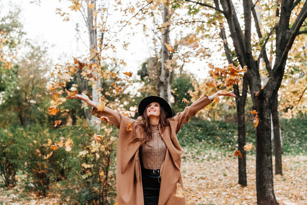menina bonita em um casaco, saia preta e jaqueta passeios de outono em um chapéu - Foto, Imagem