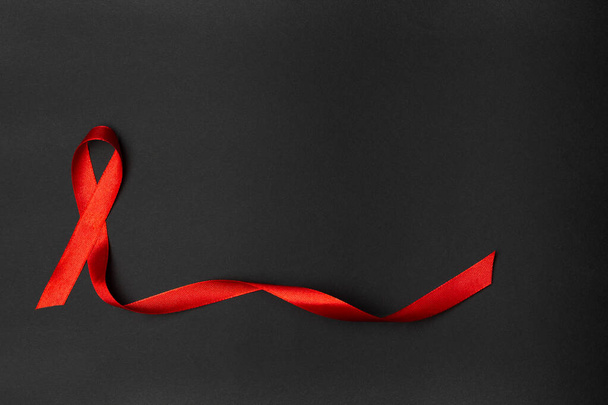 Piros szalag fekete hátterben.AIDS világnap. - Fotó, kép