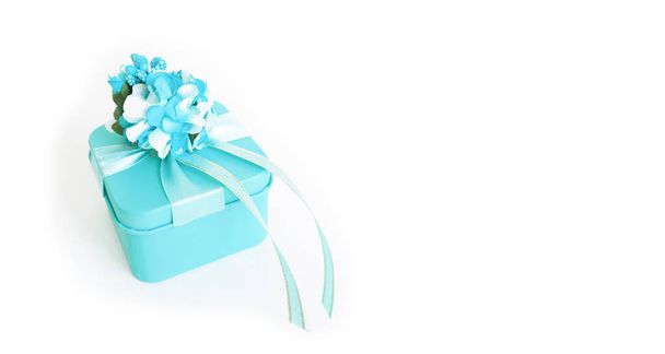 banner: uma caixa de presente azul com uma flor e fitas em um fundo branco. espaço de cópia
 - Foto, Imagem