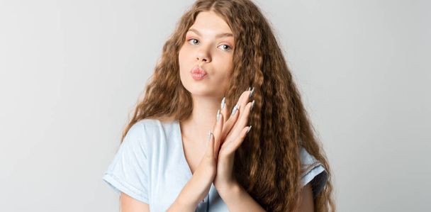 Photo of thoughtful European young woman with curly long hair looks with dreamy expression aside. Isolated over white background. - Φωτογραφία, εικόνα