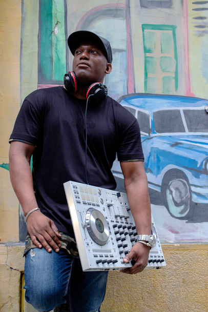  Kubański dysk dżokej z nowoczesnym sprzętem do miksowania gramofonów dj przed malarstwem ulicznym. - Zdjęcie, obraz