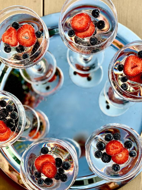Wineglasses with champagne berries and ice in the mirror background on the party - Photo, Image