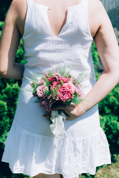 Die Braut hält einen Hochzeitsstrauß aus Rosen in der Hand, Hochzeitsblumen. Schöne Bohème Hochzeit Blumenstrauß. Mädchen in einem Kleid mit einem Rosenstrauß. - Foto, Bild