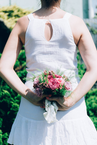 Braut Boho-Stil mit Bouquet von Pfirsichrosen. Brautstrauß in den Händen der Braut. Mädchen in einem weißen Kleid mit einem Blumenstrauß. - Foto, Bild