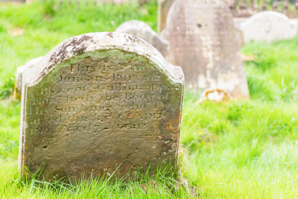 Writings on the grave  rock surounded by weed in cemetery of Ballycastle - Photo, Image