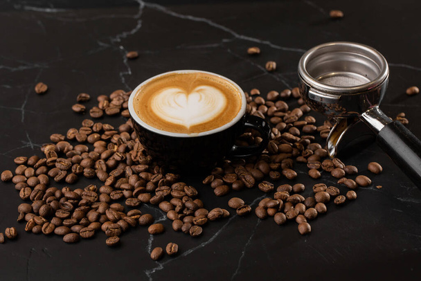 Чашка гарячої латте кави з красивою молочною піною латте текстури мистецтва з кавовим зерном на чорному мармуровому фоні. Вид зверху, місце для копіювання. Реклама меню кафе. меню кав'ярні
. - Фото, зображення