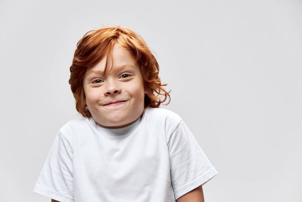 Alegre chico sonrisa rojo pelo estudio blanco camiseta recortada vista  - Foto, imagen