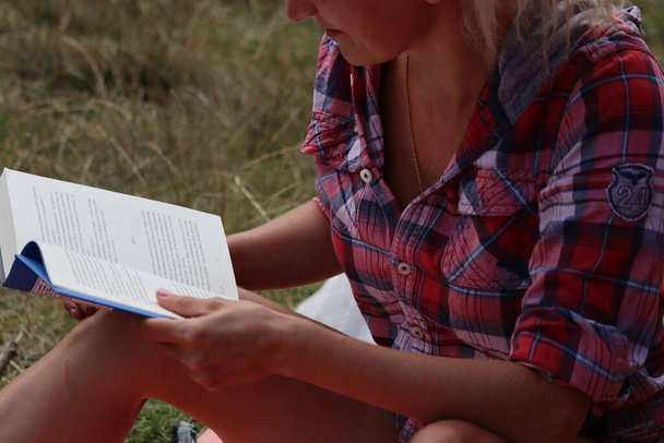Kadın oturuyor ve kitap okuyor. - Fotoğraf, Görsel