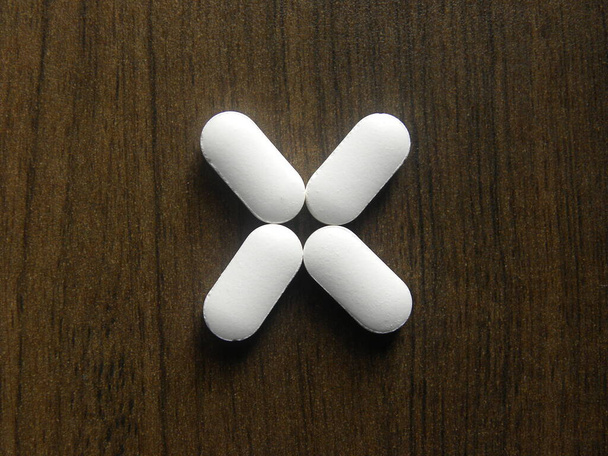 Kis hosszúkás alakú fehér gyógyszer tabletta fa alapon - Fotó, kép