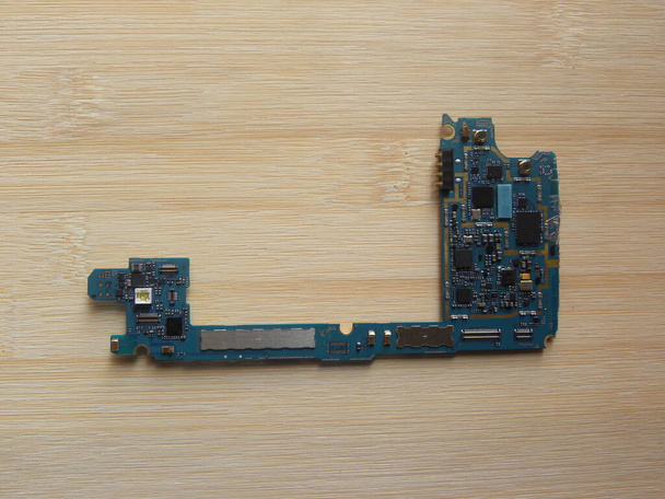 Carte de circuit imprimé pour téléphone portable conservée sur une table en bois - Photo, image