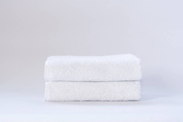 Dva bílé úhledně složené froté ručníky na světlém pozadí - Fotografie, Obrázek