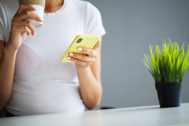 Vista frontal de cerca joven mujer sosteniendo el teléfono inteligente, escribiendo mensaje, charlando con amigos en las redes sociales. - Foto, imagen