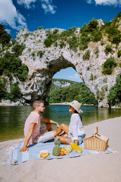 pareja en la playa junto al río en el Ardeche Francia Pont d Arc, Ardeche Francia, vista del arco narural en Vallon Pont Darc en el cañón de Ardeche en Francia - Foto, Imagen